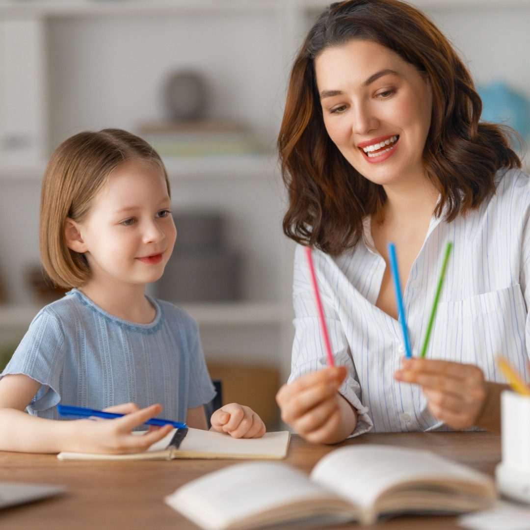 Happy child and adult are sitting at desk.